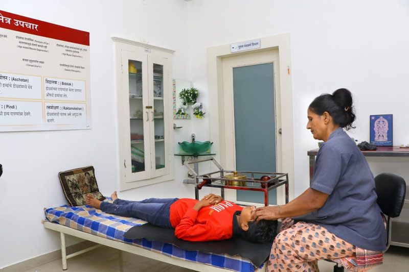 Therapist giving an Ayurvedic head therapy in Netrayu's Panchakarma department